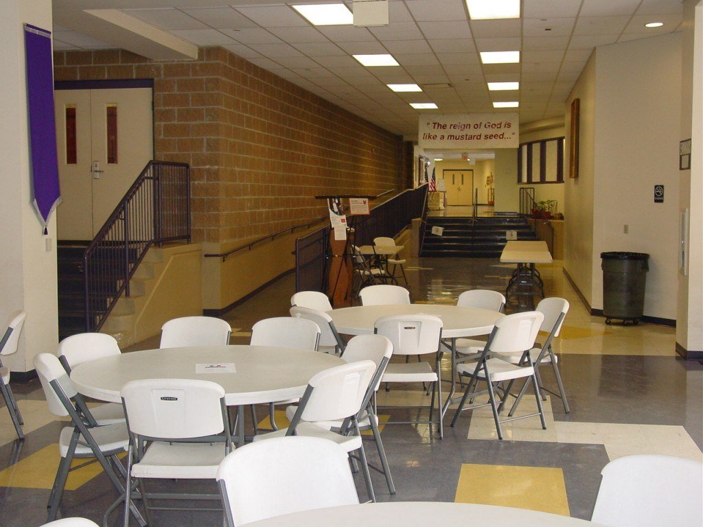 Gathering space at St. Rita's Parish with white round tables and white folding chairs