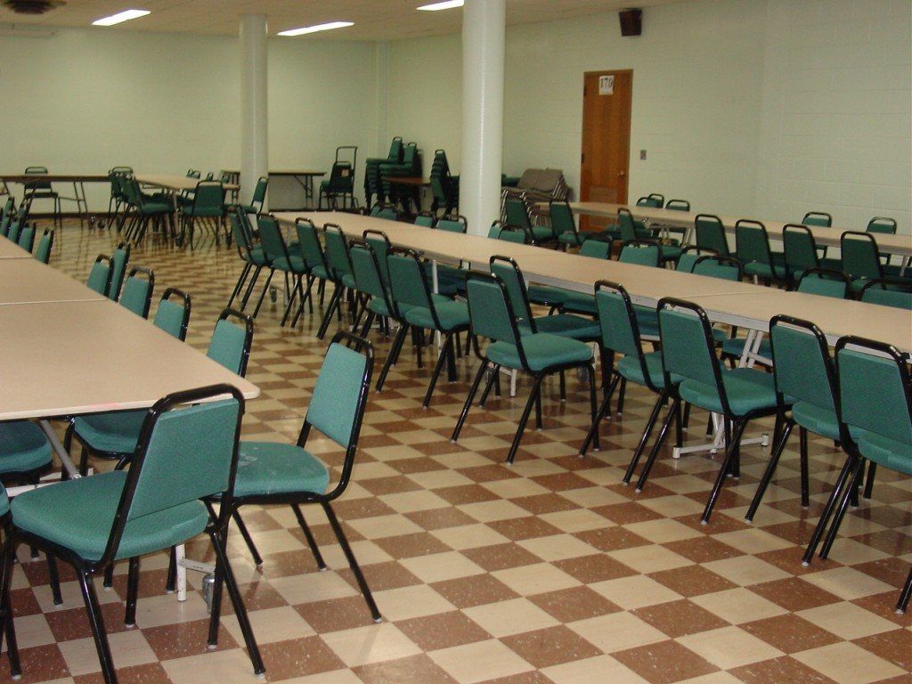 Lampe Hall in St. Rita's Parish with brown and tan checkered floors and green chairs around long tables.